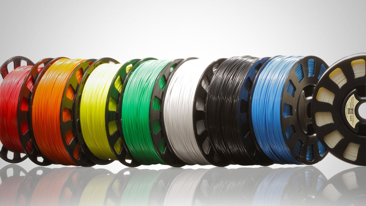 Eight rolls of different-colored filament next to each other