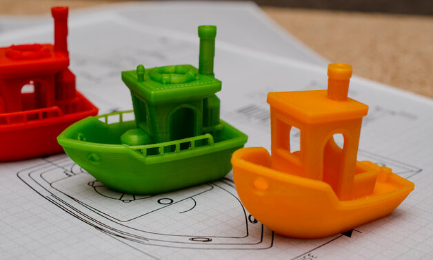 A couple of floating 3DBenchy's next to an original Benchy.