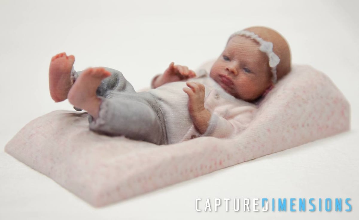 A 3D printed model of a baby sleeping, bow and all.