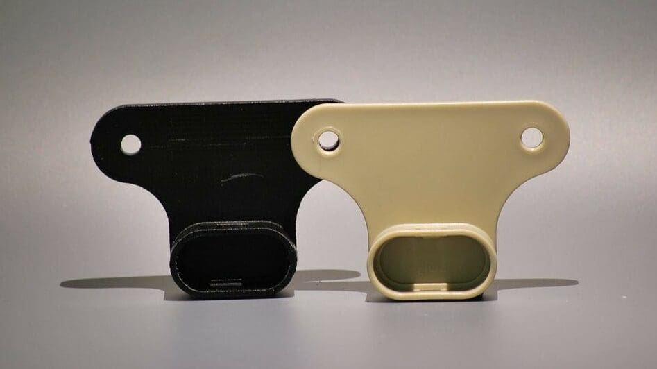 A 3D printed rail mount alongside the real thing